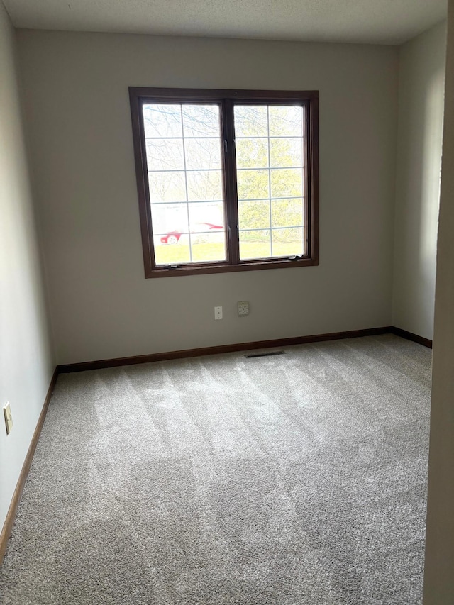 unfurnished room featuring visible vents, baseboards, and carpet flooring