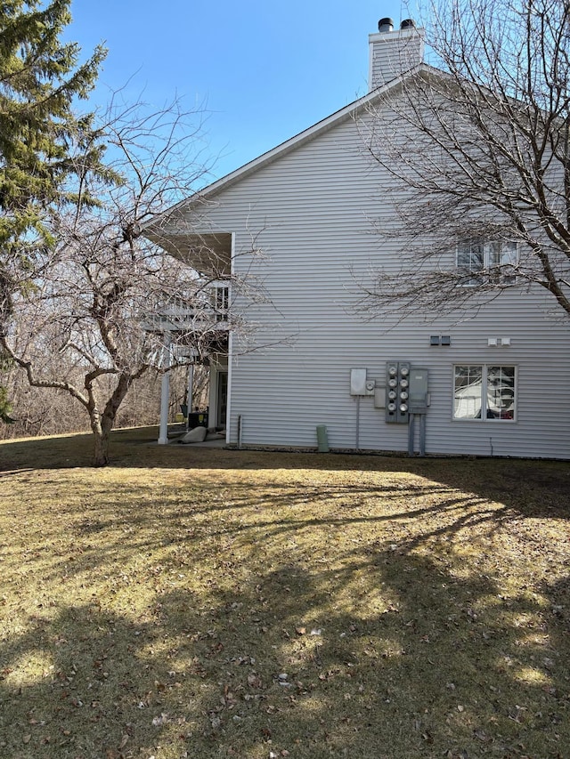 view of side of property with a lawn and a chimney