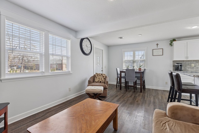living room featuring dark wood-type flooring, beamed ceiling, and baseboards