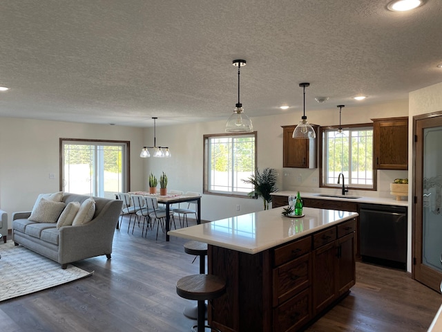 kitchen with dark wood-style flooring, light countertops, a textured ceiling, dishwasher, and a sink