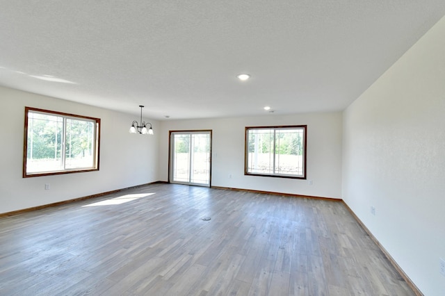 spare room featuring baseboards, a chandelier, and wood finished floors