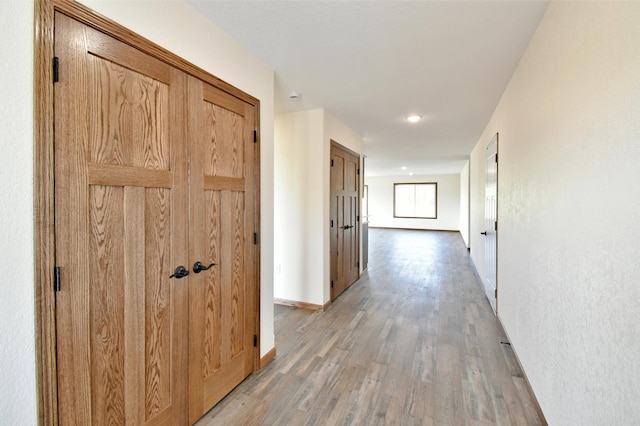 corridor featuring light wood finished floors and baseboards