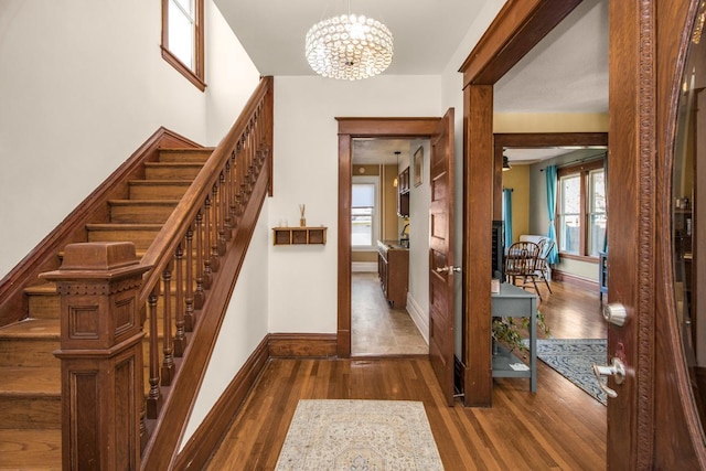 foyer entrance with an inviting chandelier, dark wood-style flooring, and a healthy amount of sunlight