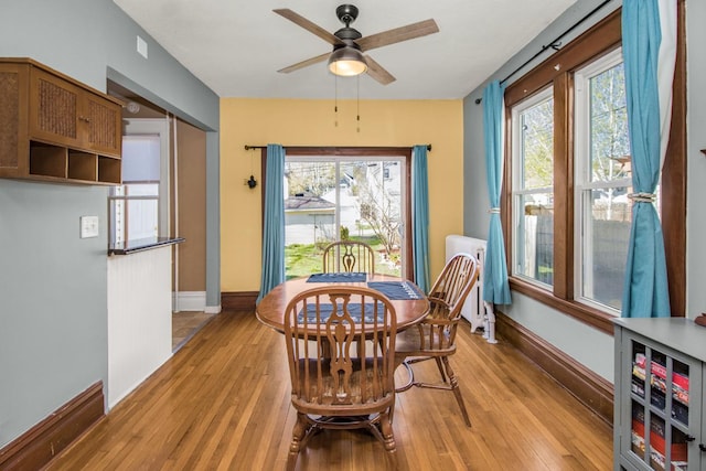 dining room with light wood-style floors, baseboards, plenty of natural light, and a ceiling fan