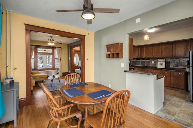 dining room featuring light wood-style floors, radiator, and ceiling fan