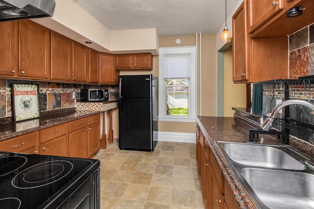 kitchen with a sink, brown cabinetry, baseboards, tasteful backsplash, and black appliances
