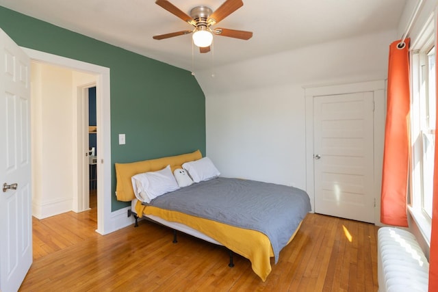bedroom with light wood-style floors, radiator, a ceiling fan, and lofted ceiling