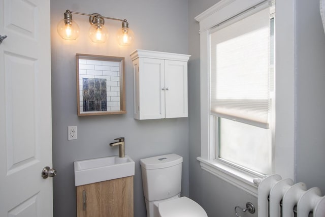 half bath featuring toilet, radiator, and vanity