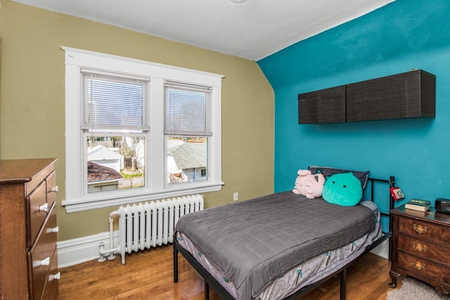 bedroom with baseboards, radiator, and wood finished floors