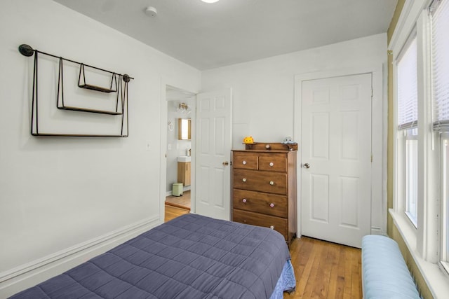 bedroom with light wood-type flooring, radiator, and baseboards
