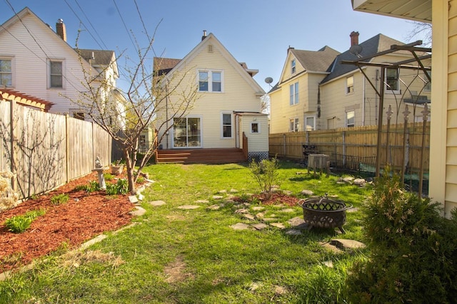 back of property with a lawn, a fenced backyard, a fire pit, and cooling unit