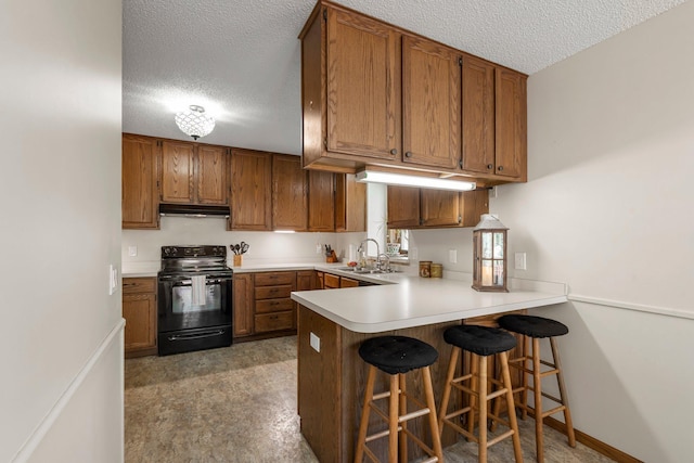 7165 Upper 157th St W, Apple Valley, MN 55124 - kitchen with black / electric stove, under cabinet range hood, a textured ceiling, a peninsula, and brown cabinets