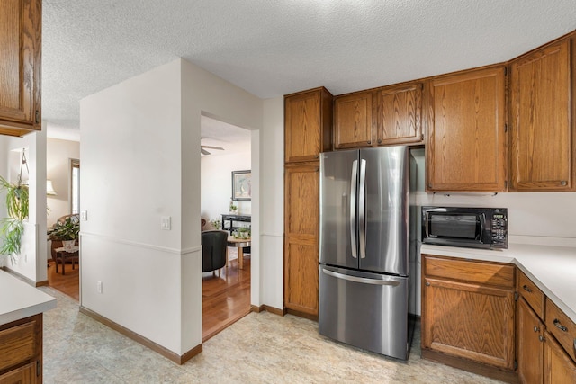 7165 Upper 157th St W, Apple Valley, MN 55124 - kitchen with freestanding refrigerator, black microwave, brown cabinets, light countertops, and a textured ceiling