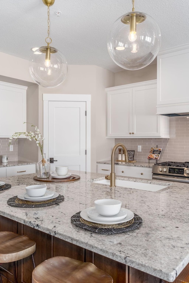 2315 Simply Living Ln Unit C, Hudson, WI 54016 - kitchen featuring stainless steel gas range oven, white cabinetry, a breakfast bar area, tasteful backsplash, and a textured ceiling