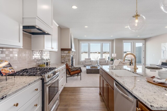 2315 Simply Living Ln Unit C, Hudson, WI 54016 - kitchen featuring appliances with stainless steel finishes, open floor plan, light wood-style floors, white cabinetry, and hanging light fixtures