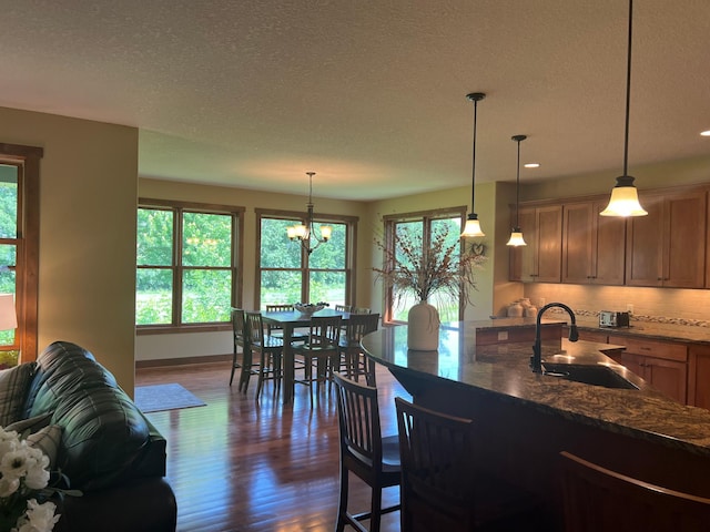 8871 Kahl Way NE, Otsego, MN 55362 - kitchen with dark wood-style floors, decorative backsplash, a textured ceiling, dark stone counters, and a chandelier