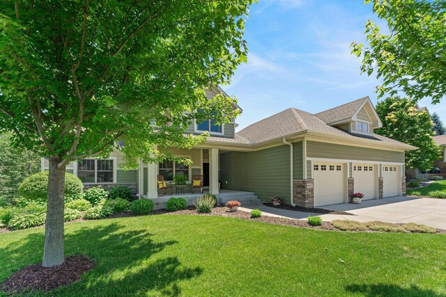 8871 Kahl Way NE, Otsego, MN 55362 - view of front of home with covered porch, a front yard, driveway, an attached garage, and stone siding
