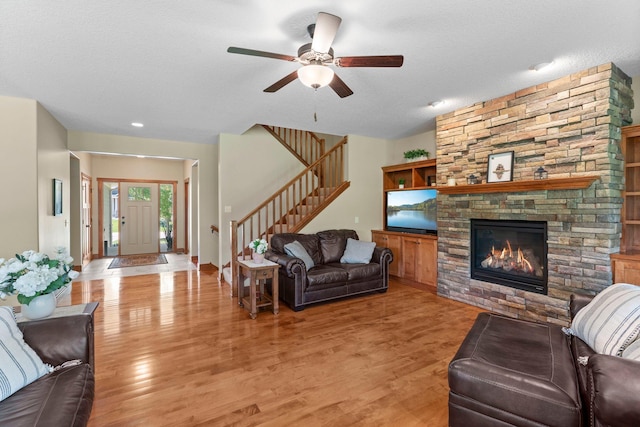 8871 Kahl Way NE, Otsego, MN 55362 - living area featuring stairs, a ceiling fan, light wood finished floors, a stone fireplace, and a textured ceiling
