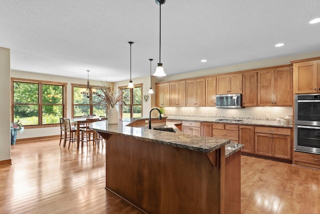 8871 Kahl Way NE, Otsego, MN 55362 - kitchen featuring appliances with stainless steel finishes, light wood finished floors, plenty of natural light, dark stone countertops, and recessed lighting