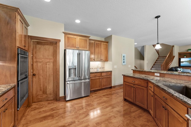8871 Kahl Way NE, Otsego, MN 55362 - kitchen featuring stainless steel appliances, brown cabinets, light wood-type flooring, dark stone countertops, and recessed lighting