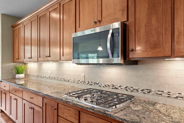 8871 Kahl Way NE, Otsego, MN 55362 - kitchen featuring appliances with stainless steel finishes, tasteful backsplash, dark stone countertops, and brown cabinets