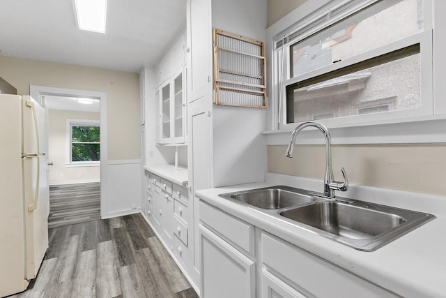 kitchen with light countertops, freestanding refrigerator, white cabinets, dark wood finished floors, and a sink