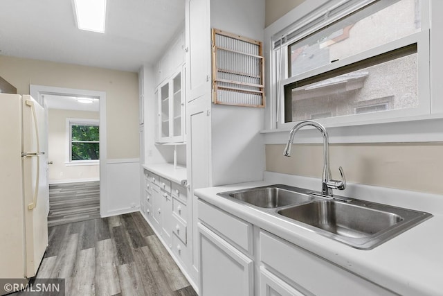 kitchen with white cabinets, a sink, light countertops, freestanding refrigerator, and dark wood finished floors