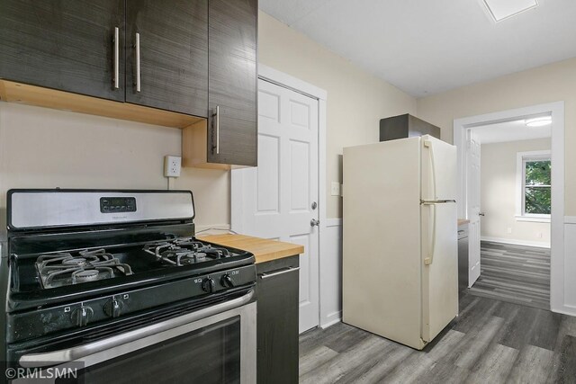 kitchen featuring wooden counters, stainless steel range with gas stovetop, freestanding refrigerator, and dark wood finished floors
