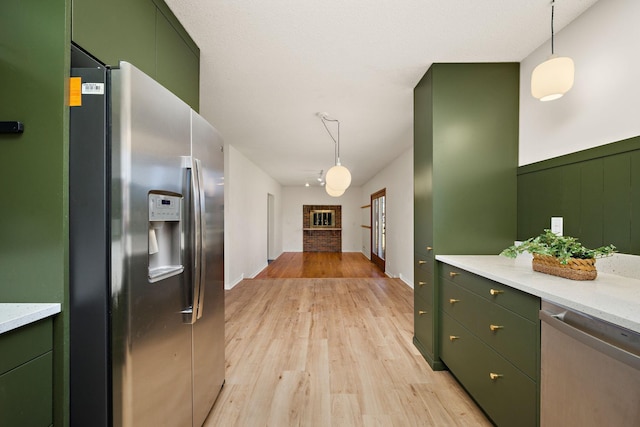 kitchen with decorative light fixtures, green cabinetry, appliances with stainless steel finishes, and light wood-style flooring