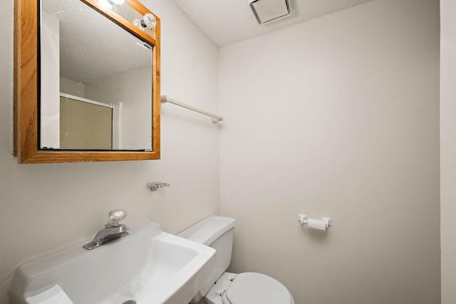 bathroom featuring a sink, toilet, and a shower stall