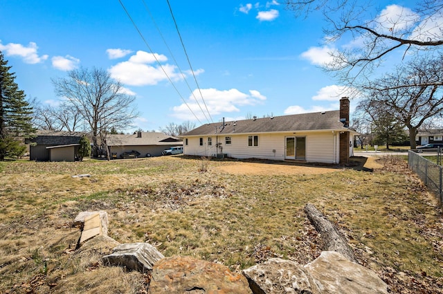 rear view of house featuring fence, a chimney, and a lawn