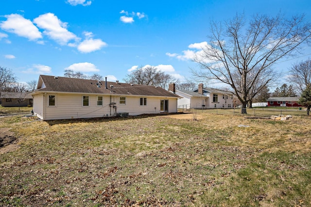 rear view of property featuring a lawn, fence, and a chimney