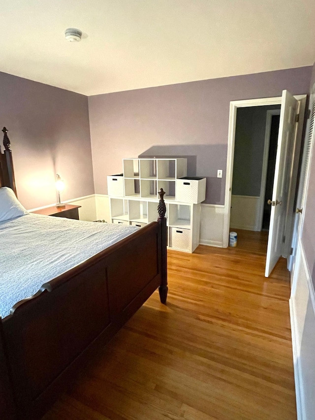 bedroom with a wainscoted wall and wood finished floors