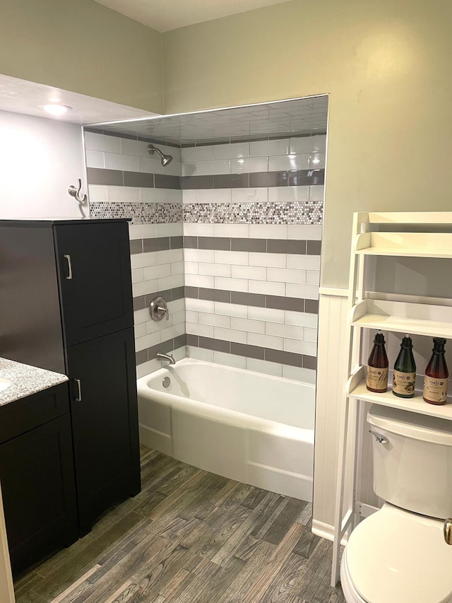 bathroom with toilet, wood finished floors, vanity, and washtub / shower combination