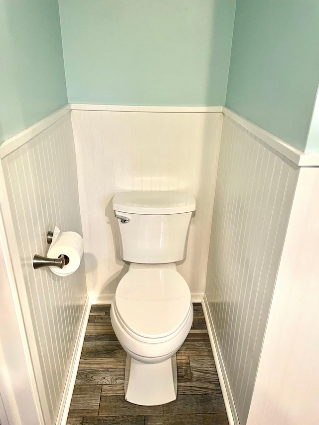 bathroom with toilet, a wainscoted wall, and wood finished floors