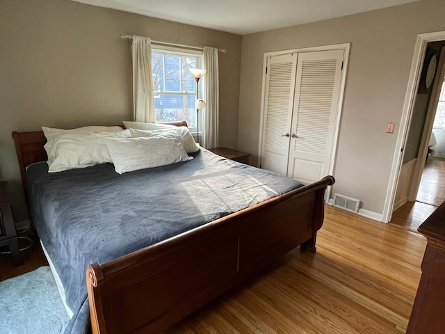 bedroom featuring visible vents, a closet, baseboards, and wood finished floors