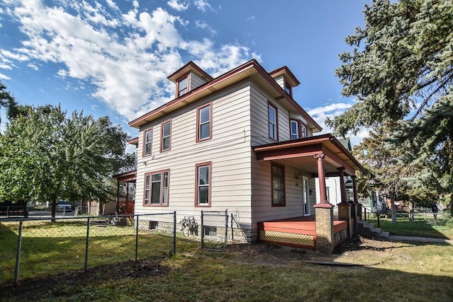 view of home's exterior with fence, covered porch, and a lawn