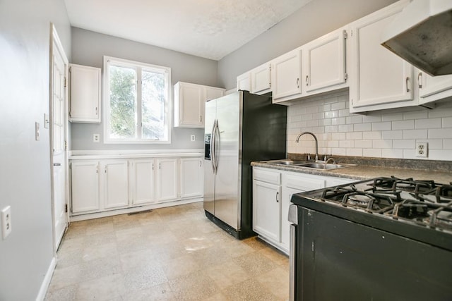kitchen with white cabinetry, stainless steel fridge, gas range oven, and extractor fan