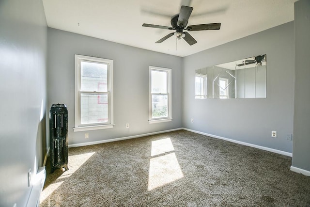 carpeted empty room with a wealth of natural light, baseboards, and ceiling fan