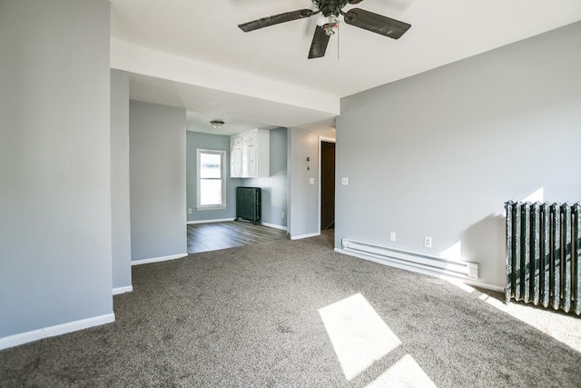 interior space with baseboards, a baseboard heating unit, a ceiling fan, and radiator