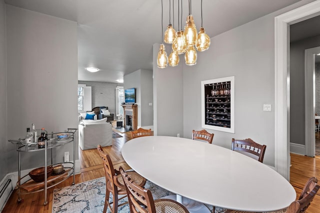 438 Portland Ave Unit 7, Saint Paul, MN 55102 - dining area featuring a brick fireplace, wood finished floors, a chandelier, and a baseboard radiator