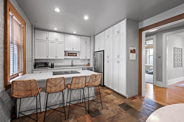 438 Portland Ave Unit 7, Saint Paul, MN 55102 - kitchen featuring appliances with stainless steel finishes, light countertops, a kitchen bar, recessed lighting, and white cabinetry