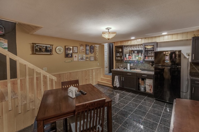 12124 County Road 118, Merrifield, MN 56465 - indoor wet bar featuring freestanding refrigerator, stairway, a wainscoted wall, wood walls, and a textured ceiling