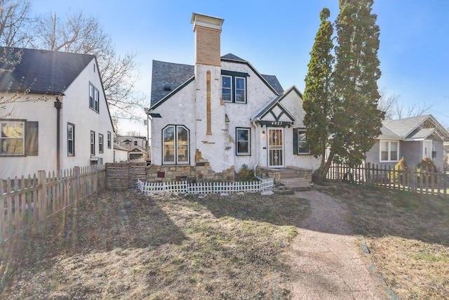 tudor home with a chimney and fence