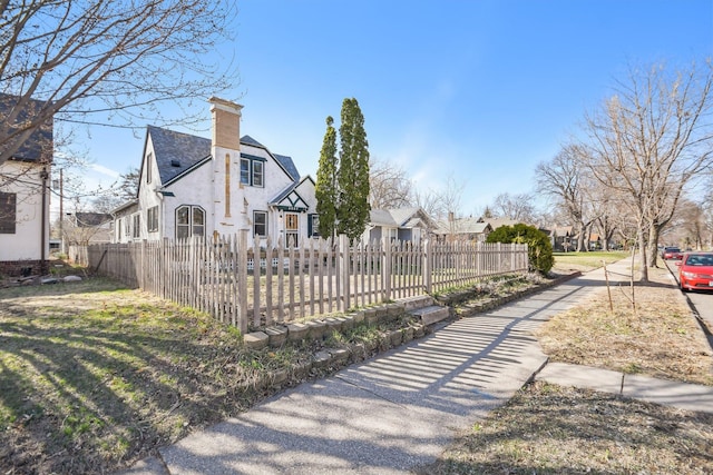 view of side of property with a chimney, a residential view, and a fenced front yard