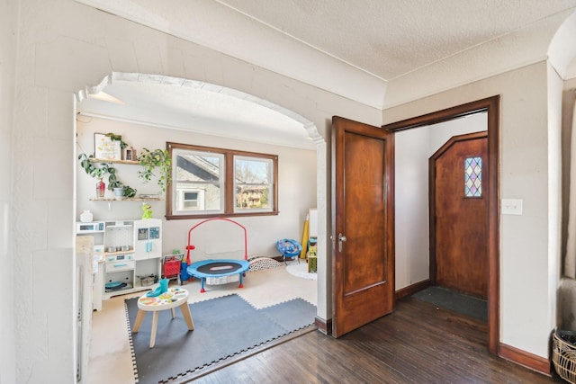 foyer featuring dark wood-style flooring and arched walkways