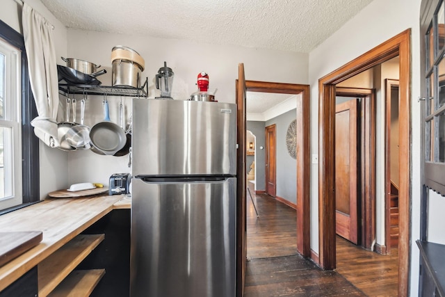 kitchen featuring a textured ceiling, freestanding refrigerator, baseboards, and dark wood-style floors