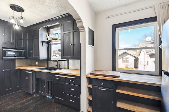 kitchen featuring dark wood-type flooring, a textured ceiling, a sink, and appliances with stainless steel finishes