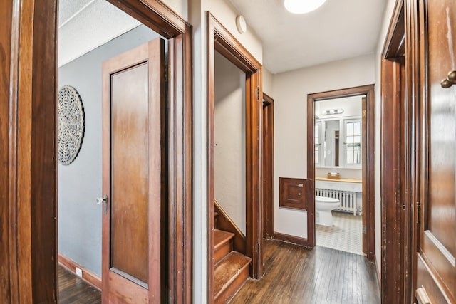 corridor with baseboards, radiator, and dark wood-style floors