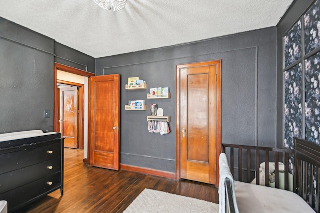 bedroom featuring a textured ceiling, a textured wall, and hardwood / wood-style flooring